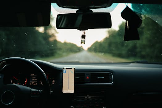 View of a car interior with a GPS on a scenic road during daytime travel.